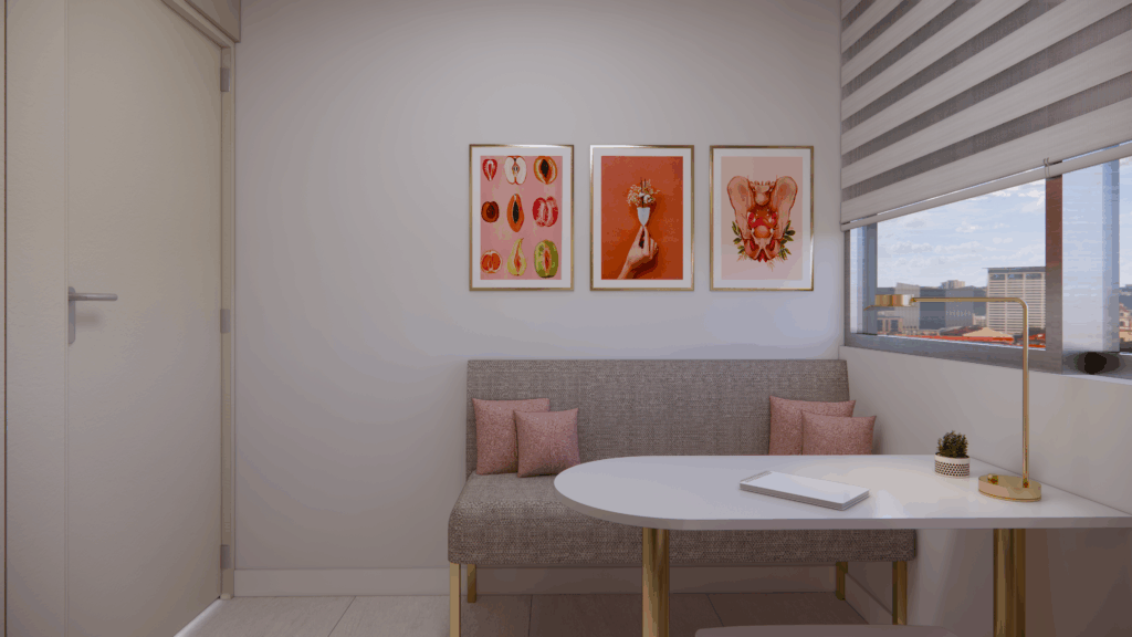 Sala de consulta con escritorio blanco, banco tapizado gris, lámpara dorada y tres cuadros de anatomía femenina.