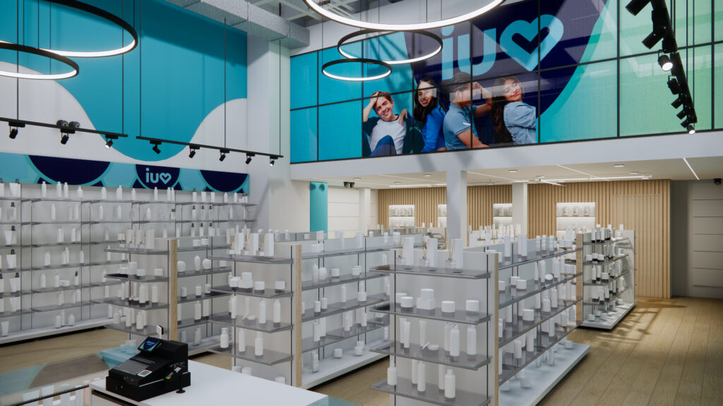 La imagen captura la arquitectura de interiores de Iuventus Store, con estanterías de productos, una mezzanina operativa con publicidad de la marca, iluminación escultural con luminarias circulares y lineales, y el uso de materiales orgánicos como paneles de madera para aportar calidez y equilibrio visual.